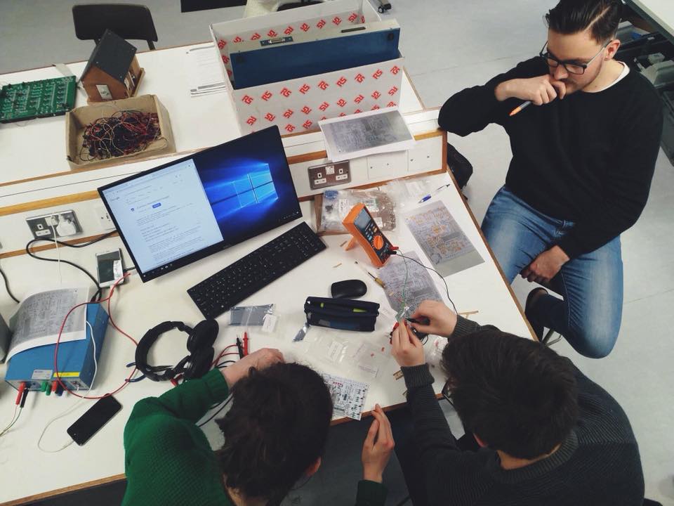 Three team members looking at the Speeduino, contemplating. 